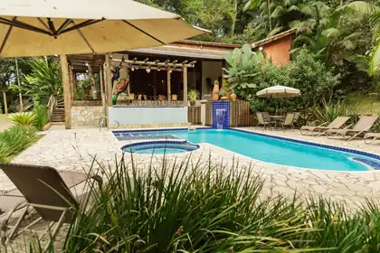 Piscina com espreguiçadeiras e o restaurante ao fundo